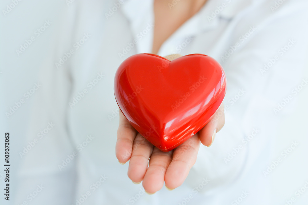 Woman holding and protecting a red heart shape