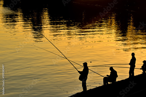 Silhouettes of fishermen in the light of the setting sun