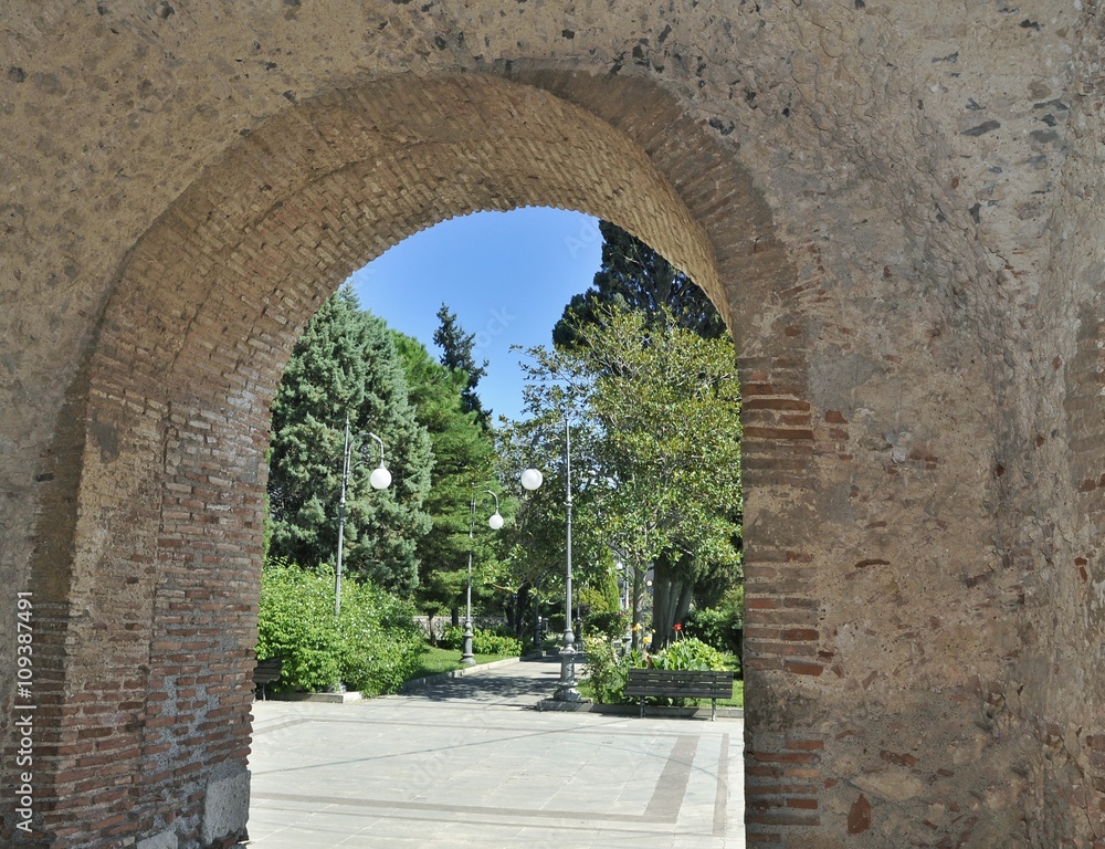 Obraz premium Old stone arch to a green park in Sicily