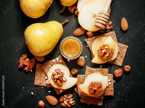 Appetizer canape with pear, honey, hazelnuts, almonds and cottag photo