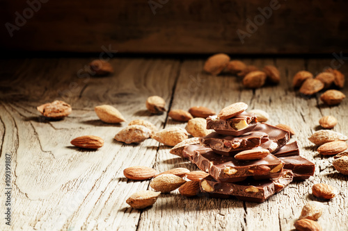 Milk chocolate with whole almonds, vintage wooden background, se