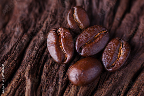 Roasted detailed tasty coffee beans with natural wooden background.