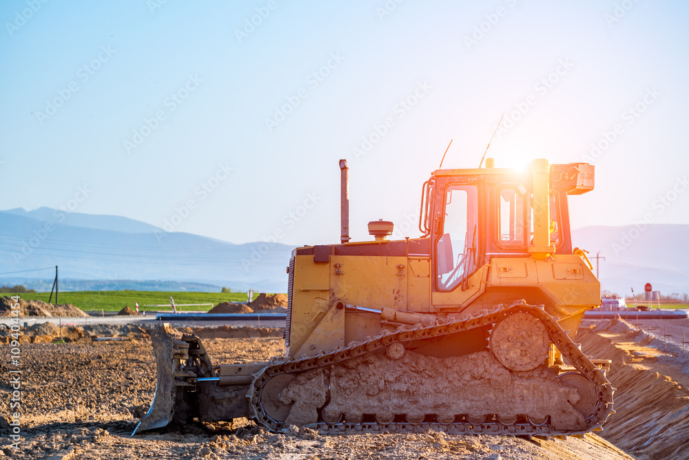 Sunset above the bulldozer working on the construction site