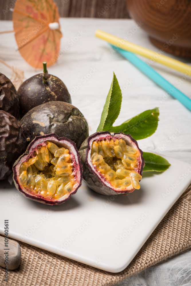 Passion fruits on white ceramic tray on wooden table background. Passion fruits on white ceramic tray on wooden table background.