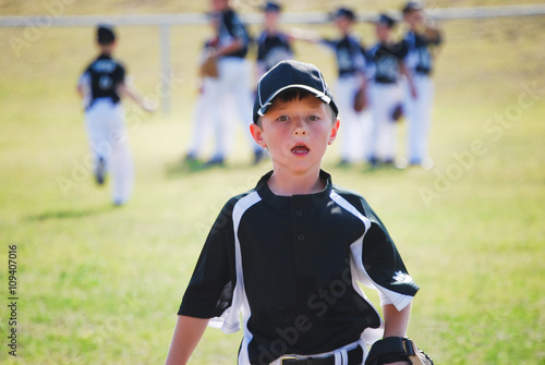 Little league baseball boy running on field.