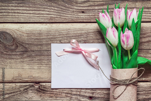 Background with blank card and bouquet of pink tulips in a brown