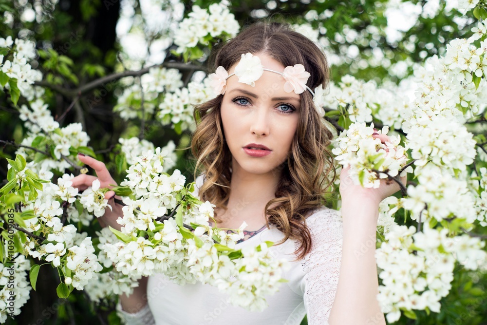 Springtime / pretty woman with flower hair band in front of a blossoming apple tree Springtime / pretty woman with flower hair band in front of a blossoming apple tree