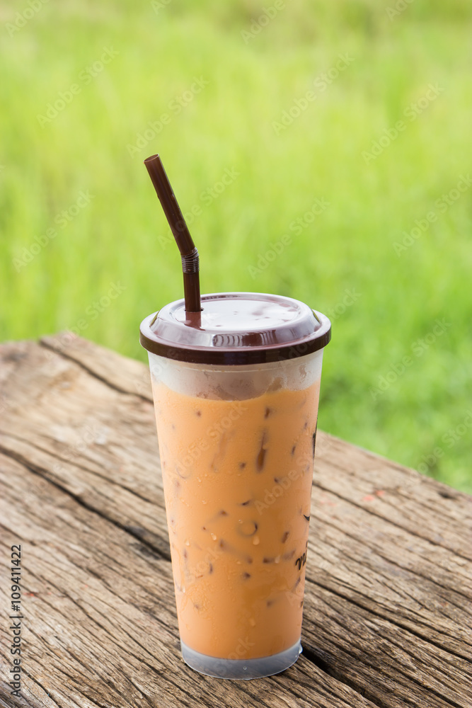 Iced milk tea in glass on wood table Iced milk tea in glass on wood table