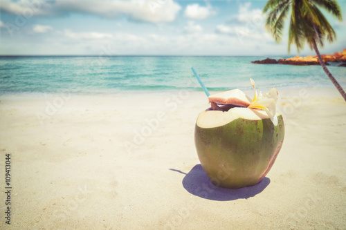 Fototapeta Naklejka Na Ścianę i Meble -  Fresh coconut cocktails with in on sandy tropical beach - vacation in summer. vintage color styles