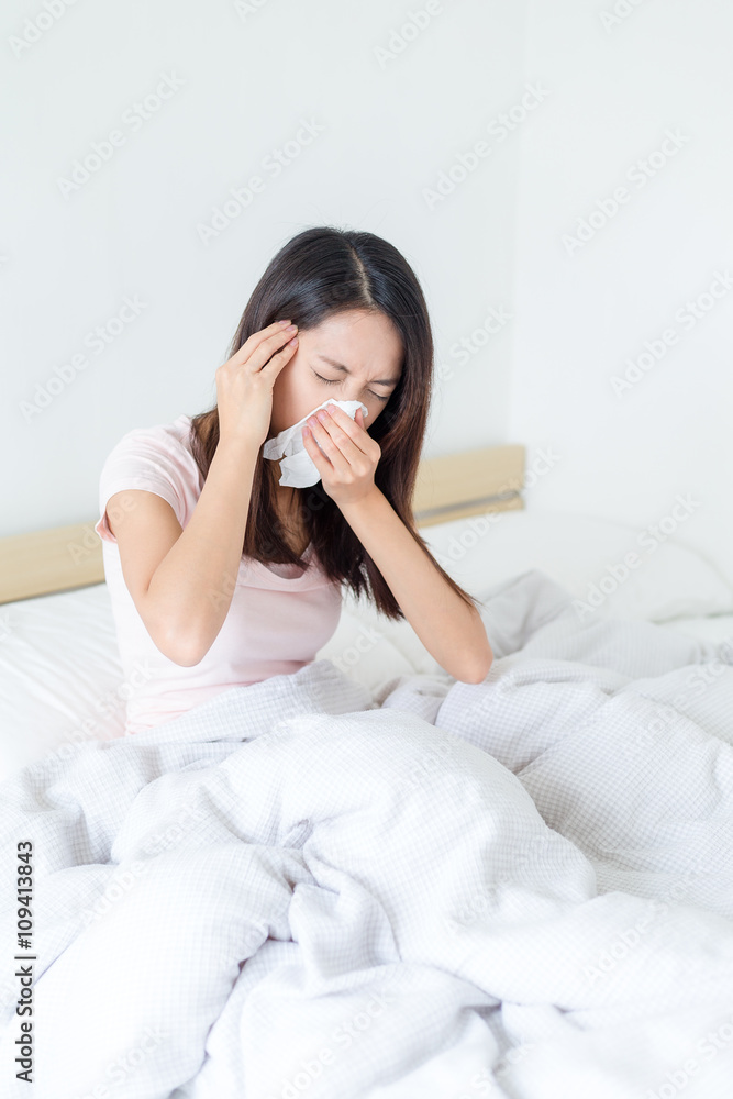 Sick woman in bed blowing her nose