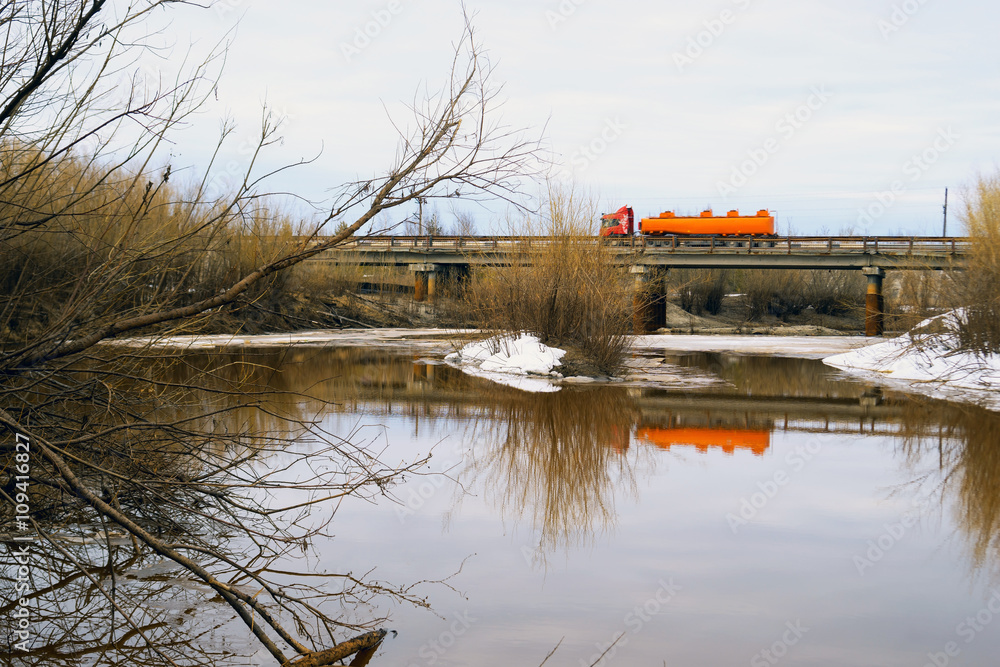 Obraz premium Truck driving on bridge over a river in the spring.