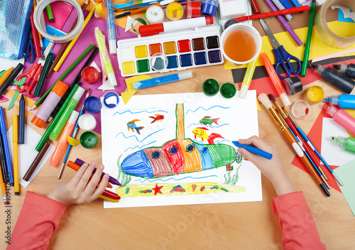 submarine and sea life child drawing , top view hands with pencil painting picture on paper, artwork workplace