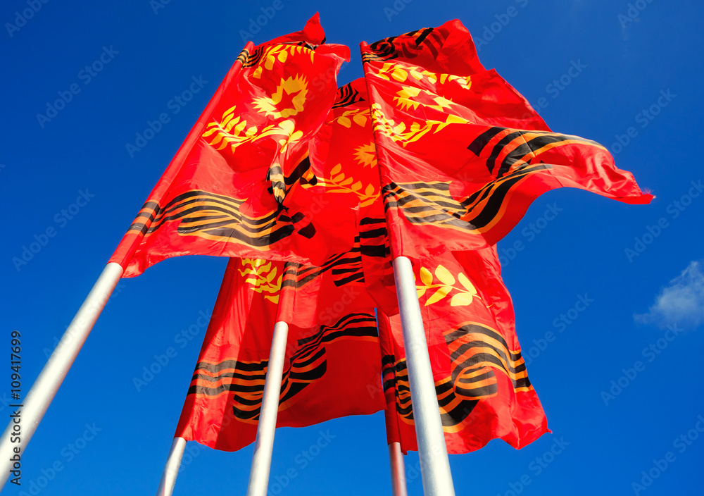 Obraz premium Red-yellow flags of the Victory developing on background blue sky.