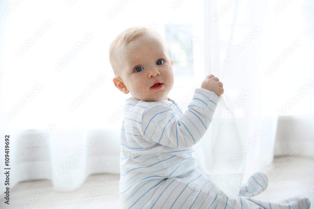 Adorable baby boy sitting on the floor, close up Adorable baby boy sitting on the floor, close up
