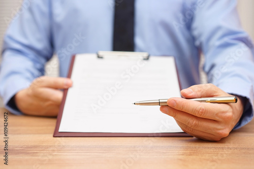 manager is offering a pen to sign a document or agreement