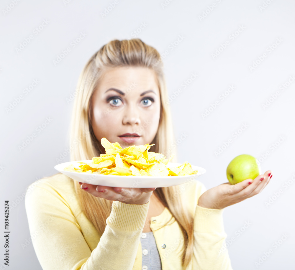 Blonde girl chooses between an apple and potato chips. Healthy food and harmful. Delicious food is unhealthy
Blonde girl chooses between an apple and potato chips. Healthy food and harmful. Delicious food is unhealthy