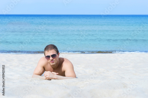 Young athletic man posing on the beach