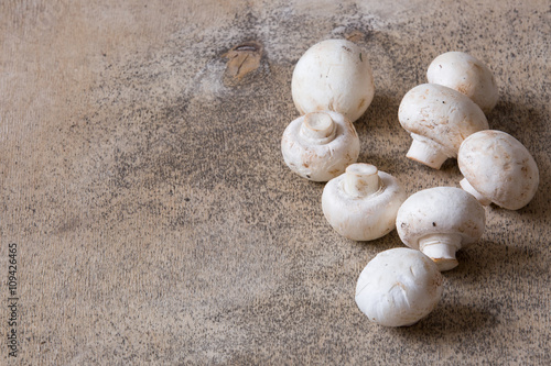 White raw champignons closeup on a wooden background. Group of fresh mushrooms on a wooden table.