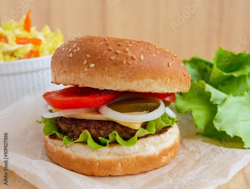 Sandwich home of the hamburger buns soft, juicy burger, cheese, tomato, parsley. Salad savoy cabbage. Fast food.