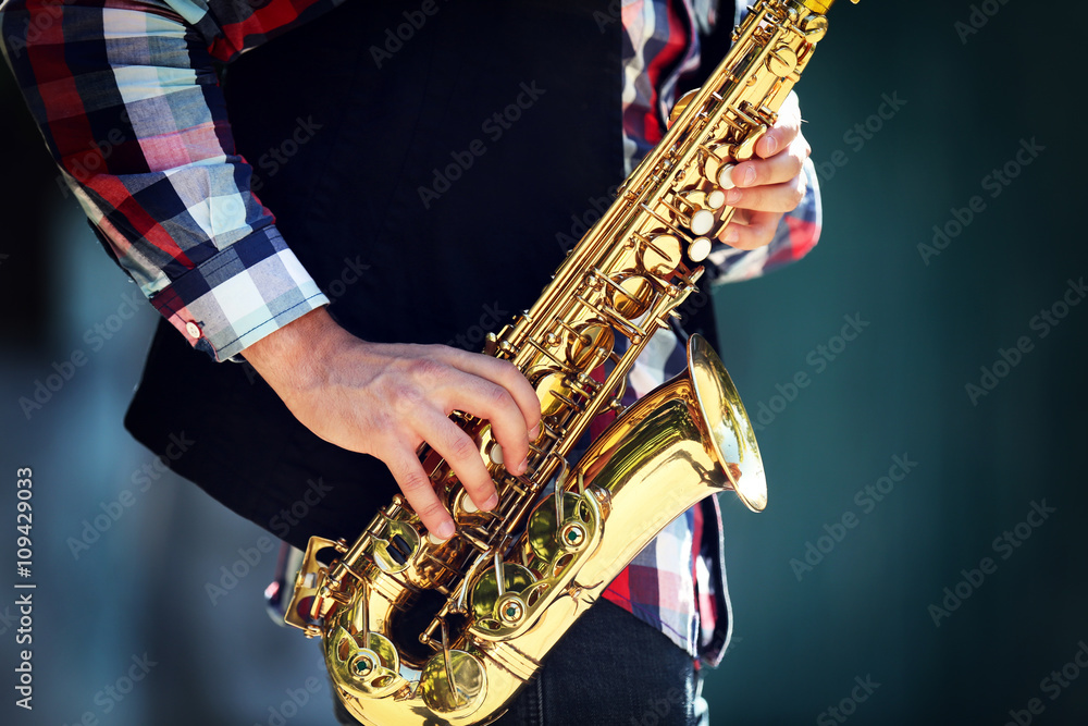 Obraz premium Young man playing on saxophone outside near the old wall