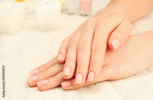 Spa concept. Woman hands with beautiful with pebbles on wooden background  close up