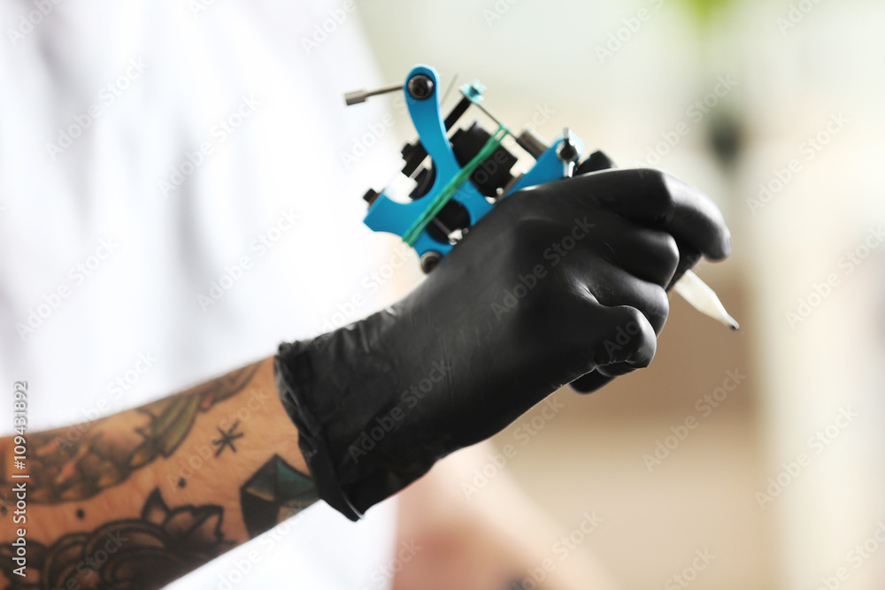 Man's hand holding tattoo machine on blurred background