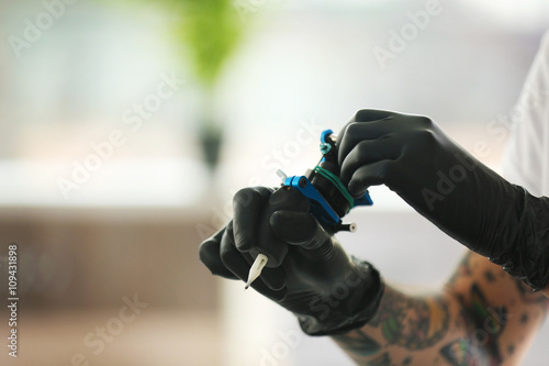 Man's hands holding tattoo machine on blurred background