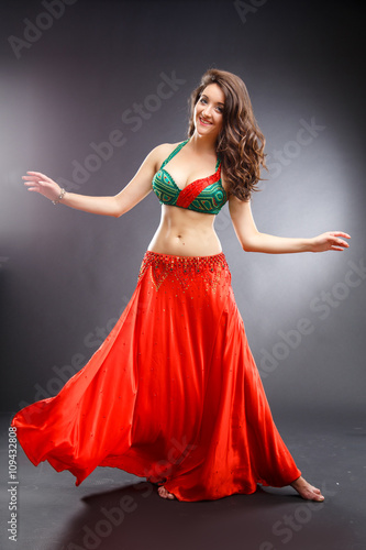 Beautiful belly dancer young woman in gorgeous red and green costume dress