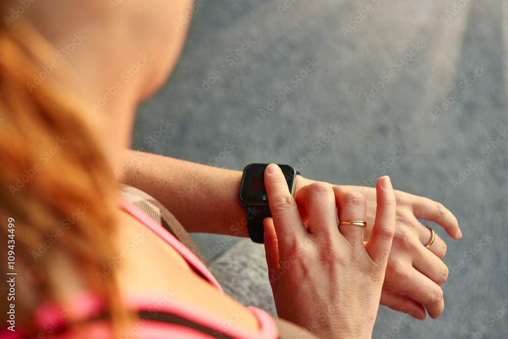 Fototapeta premium Woman programming her smartwatch before going jogging to track performance