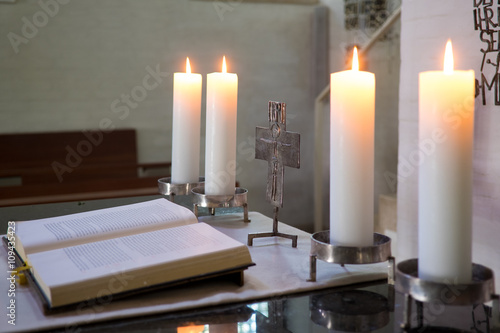 Altarraum mit Bibel, Kreuz und brennenden Kerzen photo