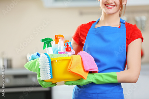 Cleaning concept. Young woman holds basin with washing fluids and rags in hands, close up