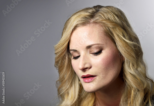 Beautiful blond woman looking down. Young, sad or thinking looking woman with copy space.
