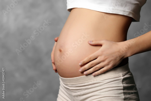 Pregnant woman on grey wall background