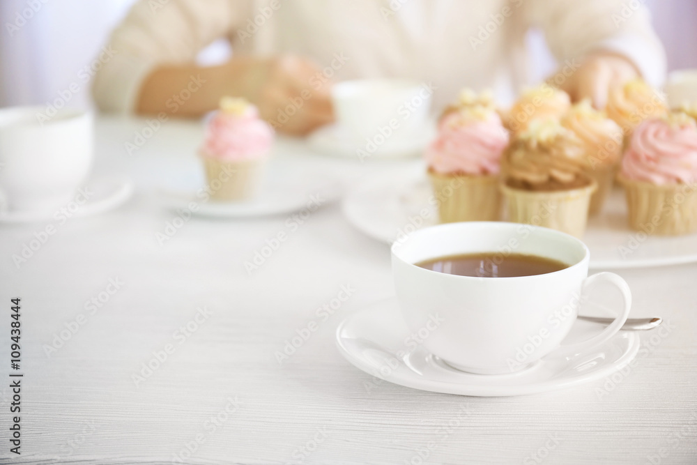 Female hands at the table with tea and cupcakes closeup Female hands at the table with tea and cupcakes closeup