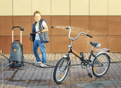 Obraz na płótnie White boy washing his bicycle with the power wash outdoors w salonie