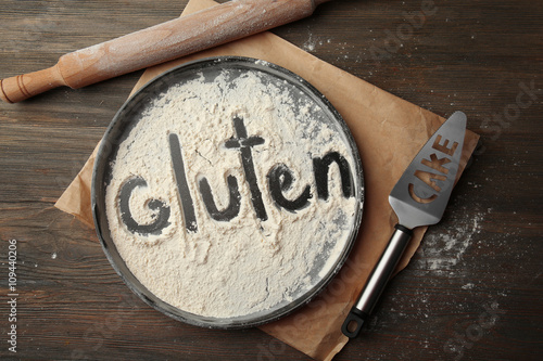 Foto Gluten word written with flour on baking utensil over wooden table