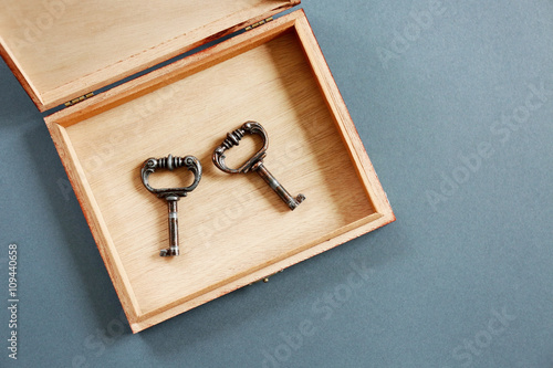 Vintage keys in a wooden box on a grey background