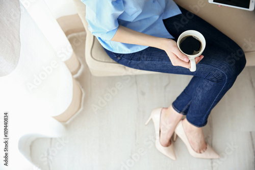 Woman holding a cup of coffee on her lap