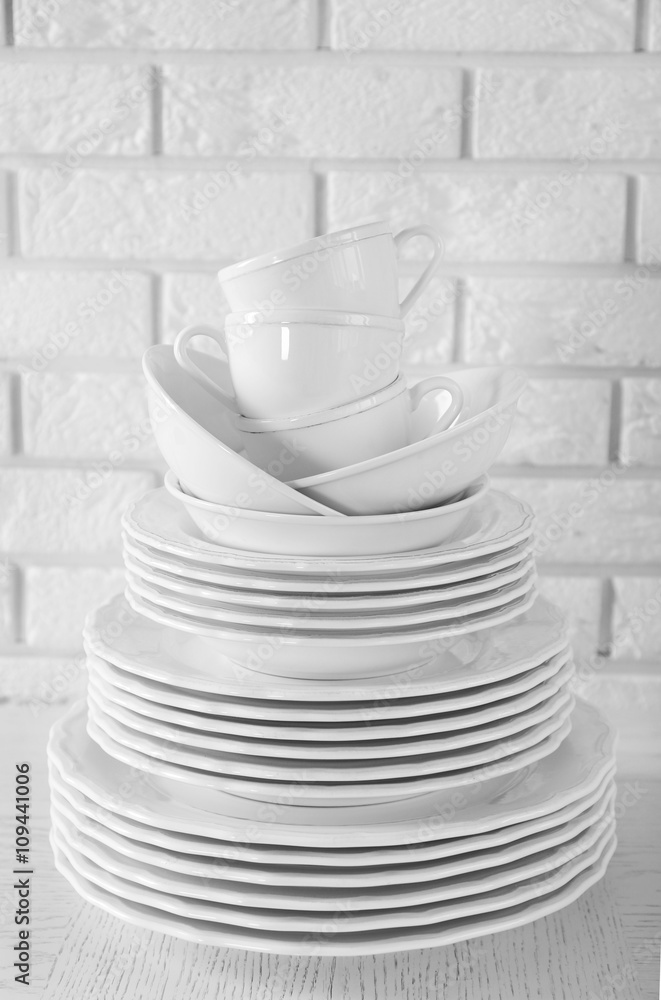 Stacked white clean plates and cups on white table Stacked white clean plates and cups on white table
