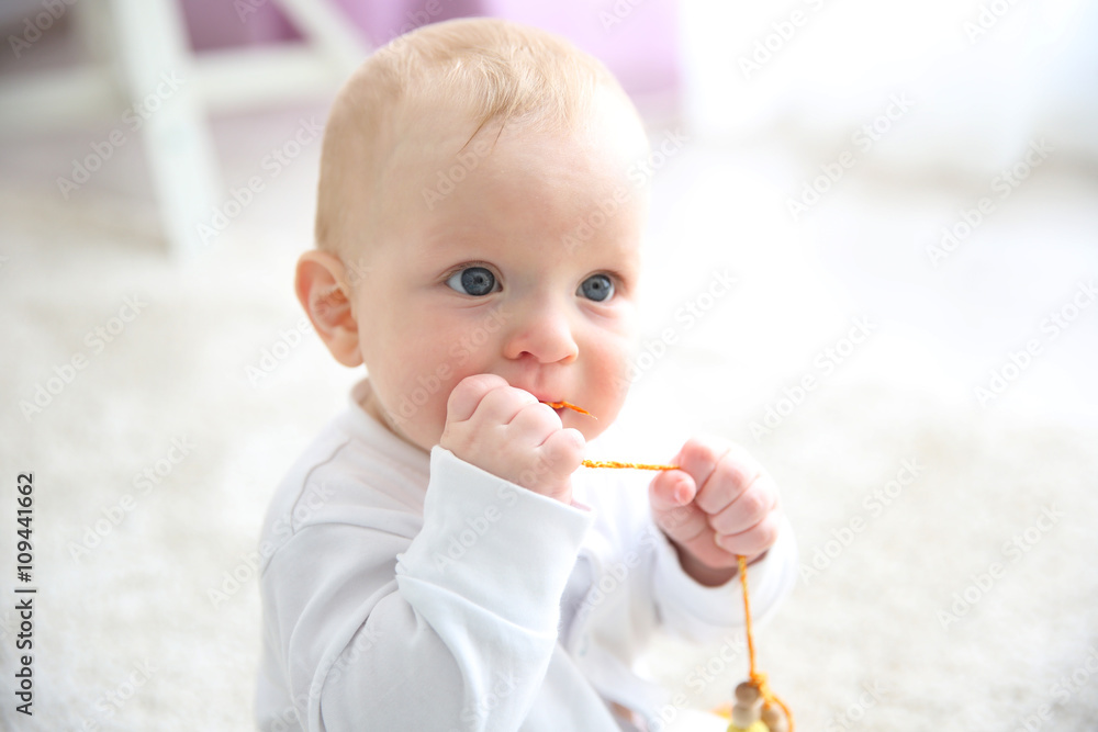 Adorable baby boy sitting on the floor, close up Adorable baby boy sitting on the floor, close up