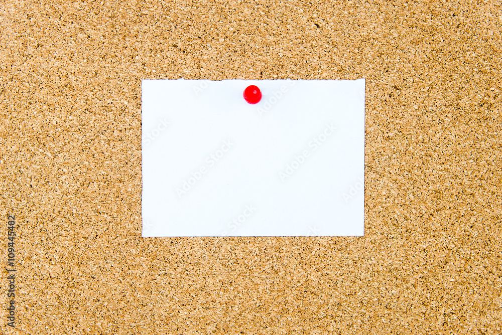 Blank white paper note pinned on cork board Blank white paper note pinned on cork board