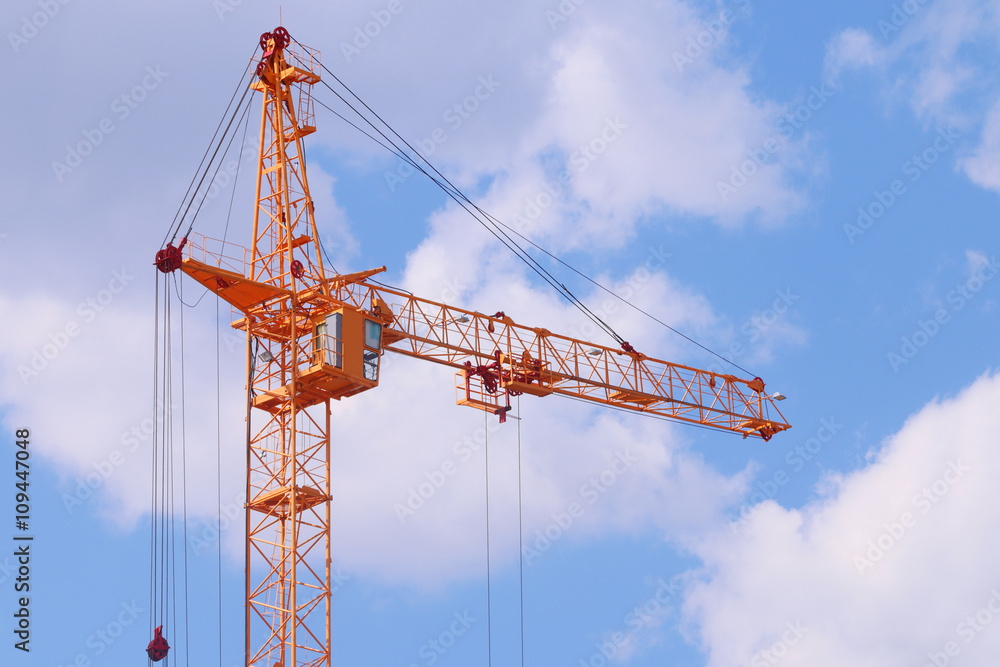 Big yellow stationary hoist on construction site, blue sky 