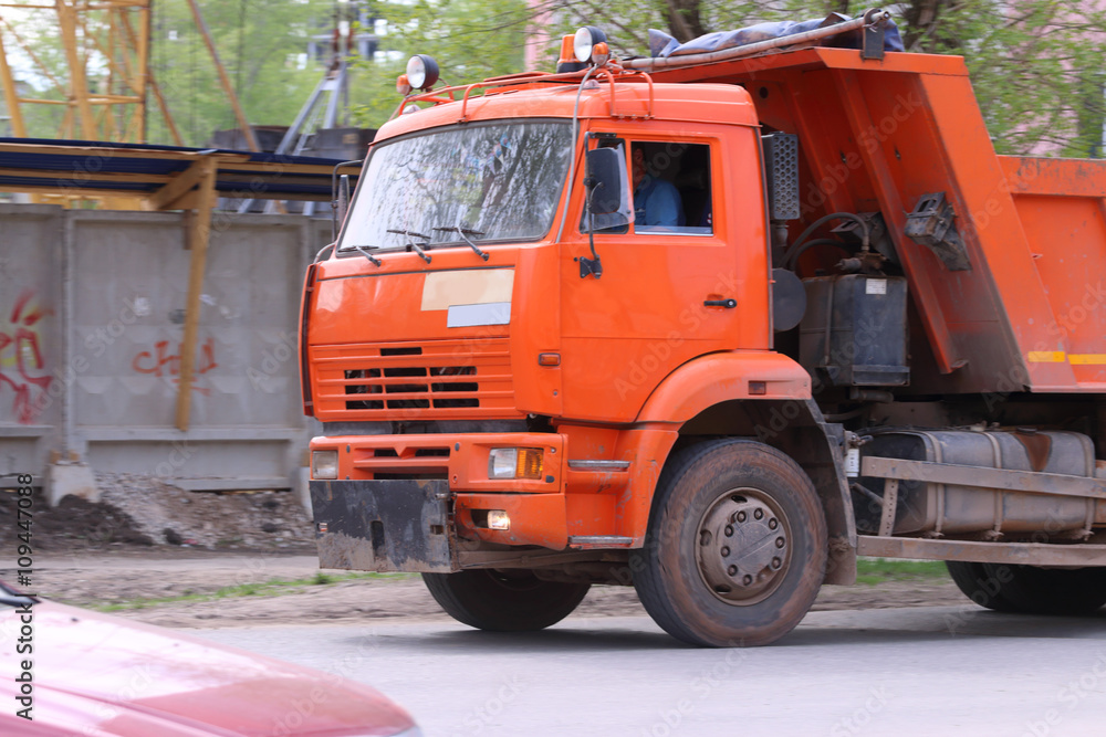 Close up of orange bright truck moving to construction site 