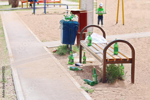Many beer bottles near bench on children playground at summer 