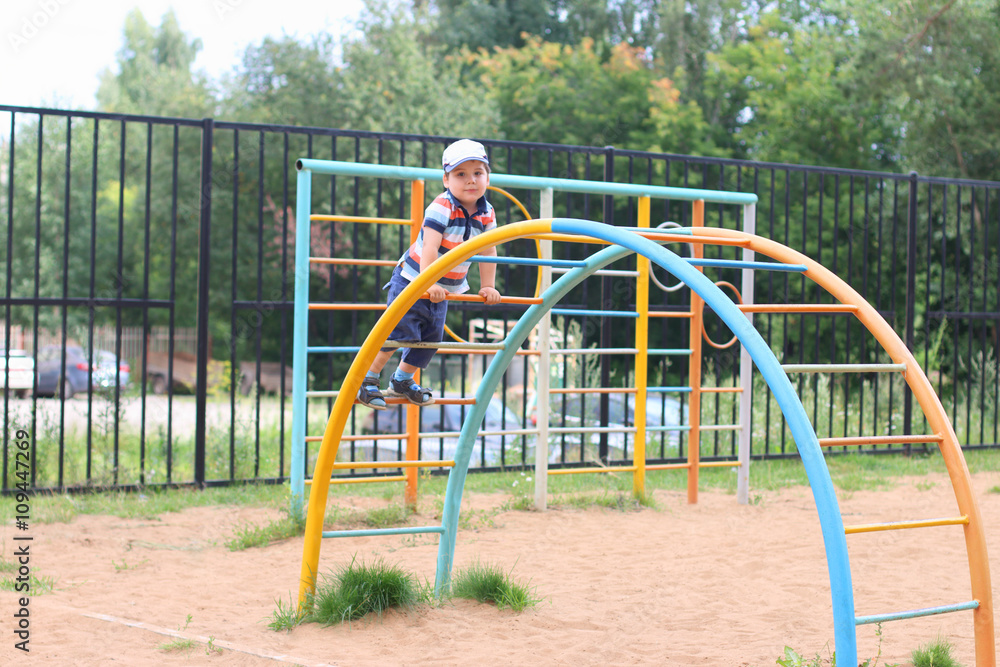 Happy little boy plays on children playground at summer day Happy little boy plays on children playground at summer day