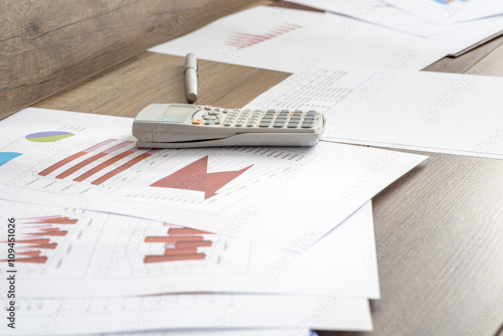Paperwork with statistical data, graphs and charts lying on a wo Paperwork with statistical data, graphs and charts lying on a wo