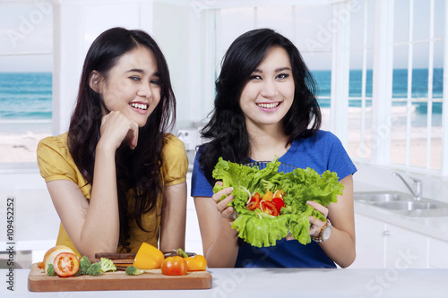 Two young women showing fresh salad