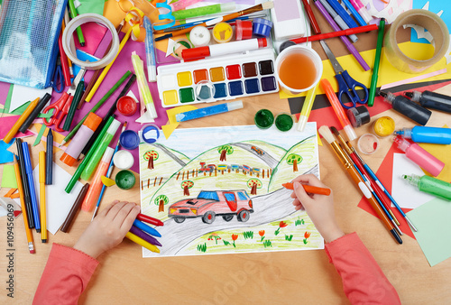red car on countryside and steam train child drawing, top view hands with pencil painting picture on paper, artwork workplace