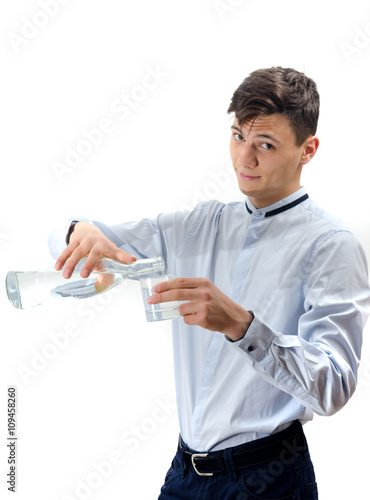 Teenager waiter pouring water from glass bottle into a glass iso