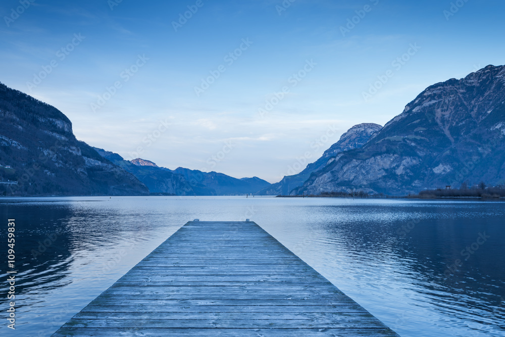 Evening. Background as epic mountain landscape.  Lake at sunset  with wooden pier.